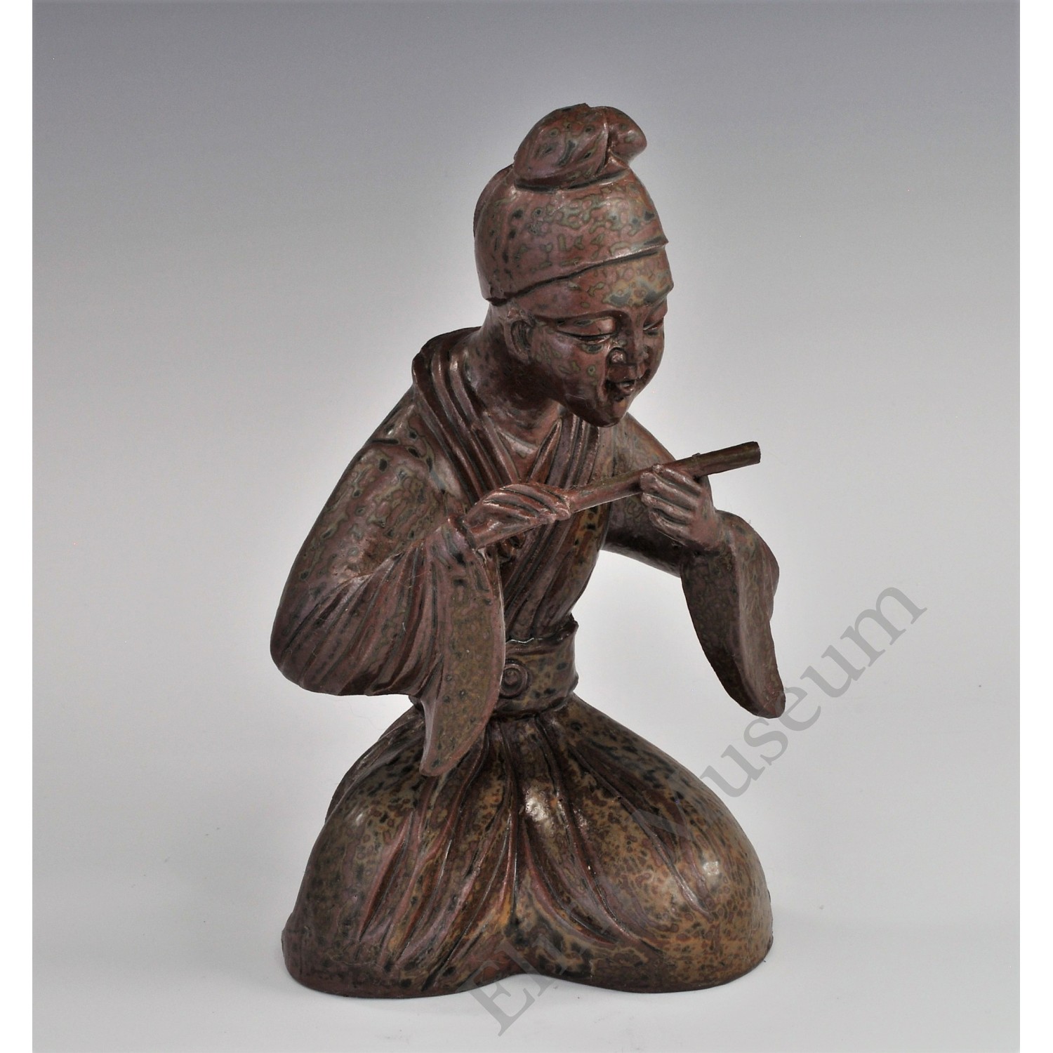 1725 A Yue ware figure of a young flute player with green decoration